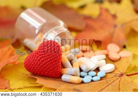Hypertension, Heart Disease And Cardiology соncept. Knitted Red Heart And Pills On Autumn Maple Leav