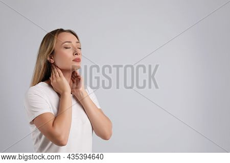 Young Woman Doing Thyroid Self Examination On Light Grey Background, Space For Text