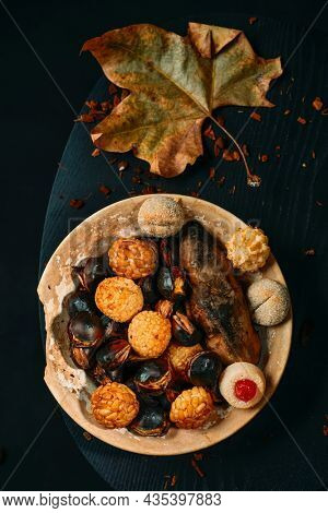 high angle view of a plate with food eaten in All Saints Day in Catalonia, Spain, in a party called Castanada, such as roasted chestnuts, sweet potato and panellets, a confection made with marzipan
