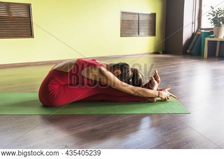 Woman Performs The Exercise Of Pashchimottanasana, The Pose Of Stretching The Western Side Of The Bo