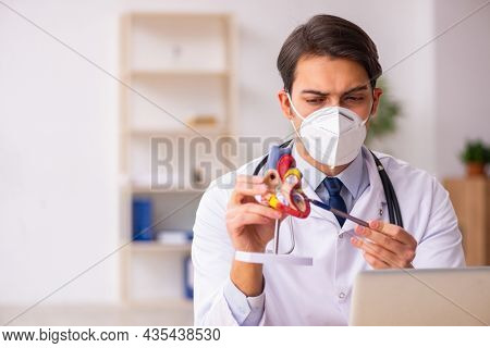 Young male doctor cardiologist working in the clinic during pand