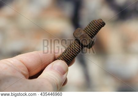 Old Rusty Bolt, Iron Rod With Screw Threads, In Hand. Rusted Mechanical Components. Holding Threaded