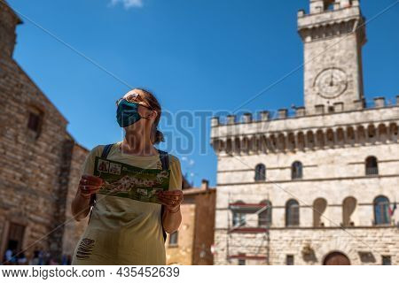 Montepulciano,tuscany,italy.august 2020. In The Town Hall Square A Caucasian Woman With A Tourist Ma