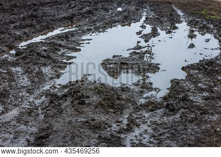 A Broken Rural Country Road. Puddles After Rain On A Dirt Road. Clay, Soil And Puddles At Cloudy Day