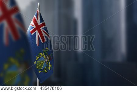 Small Flags Of Pitcairn Islands On A Blurry Background Of The City