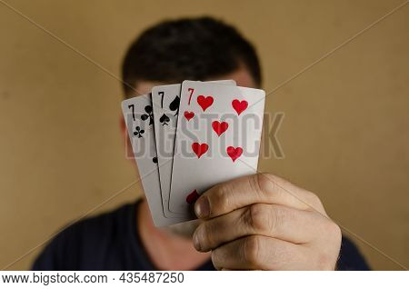 An Adult Male Holds Playing Cards In Front Of His Face. Hand With Three Playing Cards. Inside The Ro