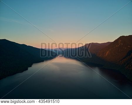 The Western Shore Of Lake Teletsky Is Set At Sunset, The Setting Sun Tingles White Cumulus Clouds Or