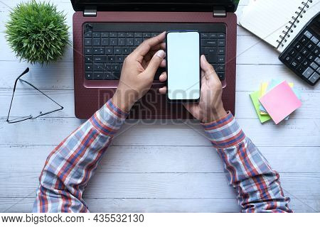 Top View Of Man Hand Using Smart Phone On Office Desk