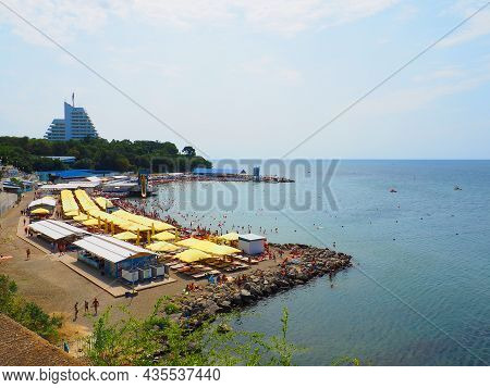 Anapa, Russia, August 23, 2021 Vysokiy Bereg Beach Or Kamenka. Stone Pebbles On The Beach. Tourists 