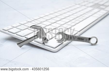 Small Hammer And Wrench Of A Chiclet Keyboard On A Concrete Table. Hardware Repair Service Concept.