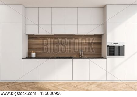 Simple Kitchen Cabinet Interior With Wood Look Splashback In Niche And Parquet Flooring. White Desig