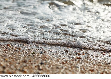 Tidal Bore. The Wave Rolls Onto The Seashore, Which Is Covered With Shells. Coastline. Sea Waves Wit