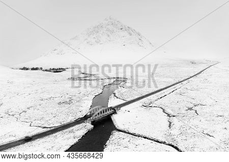Buachaille Etive Mor Mountain And Empty Road Covered In Snow During Winter