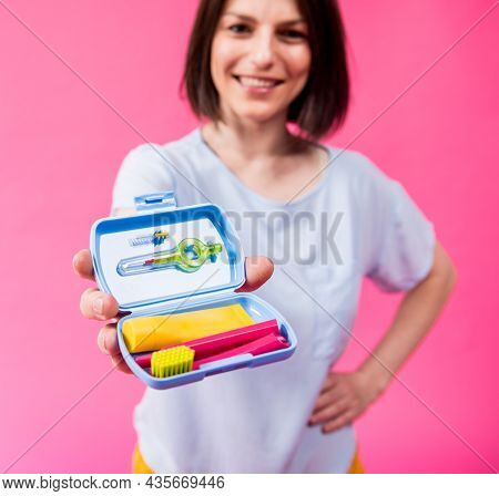 Beautiful Girl Uses A Travel Kit For Dental Care On A Pink Background