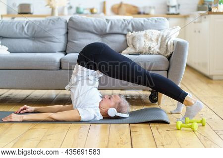 Senior Woman Stretching, Online Training In Living Room. Balancing Yoga Exercise. Exercising For Emo