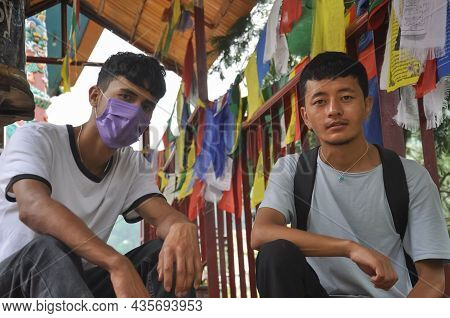 Two Male Friends Looking At Camera With Sitting On Stairs Of Buddhist Temple In Tso Pema During Covi