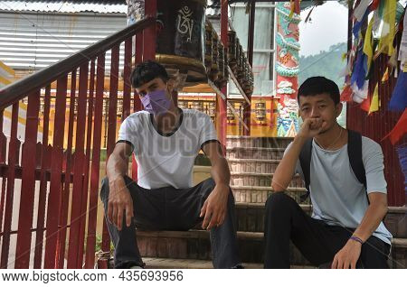 Two Male Friends Looking At Camera With Sitting On Stairs Of Buddhist Temple In Tso Pema During Covi