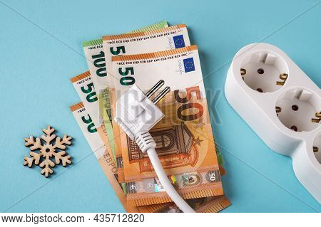 White Electric Plug On Euro Banknotes, Snowflake And Extension Socket Over Blue Background. Rise In 