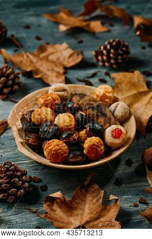 plate with some roasted chestnuts, a roasted sweet potato, and some panellets, typical confection of Catalonia, Spain, eaten traditionally in All Saints Day, in a party called Castanada, on a table