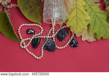 On A Red Background Lie Autumn Leaves, A Necklace And Semi-precious Stones - Hematite, Black Onyx, O
