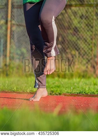 Middle Age Woman Stretching Knees And Ankles, She Jumping Bare Feet On Red Rubbery Running Track Of 
