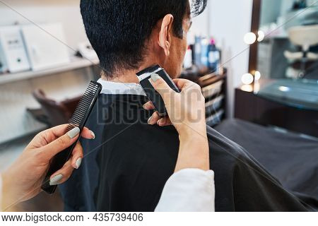 Hairdresser Using Electric Razor For Shaving Man Head Back