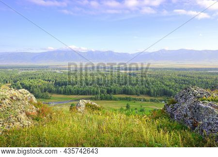 Stones On The Edge Of The Slope Above The Mountain Plain Under A Blue Cloudy Sky. Siberia, Russia