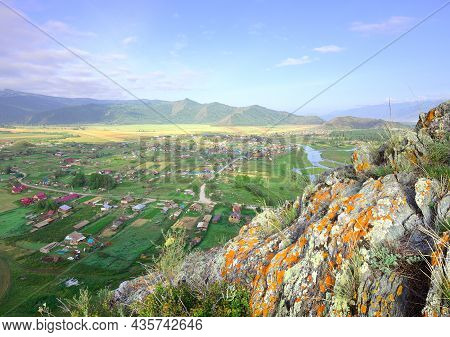 The Edge Of A Cliff Above A Mountain Valley Under A Blue Cloudy Sky. Siberia, Russia