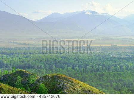 A Green Mountain Slope Above A Mountain Plain Under A Blue Sky . Siberia, Russia