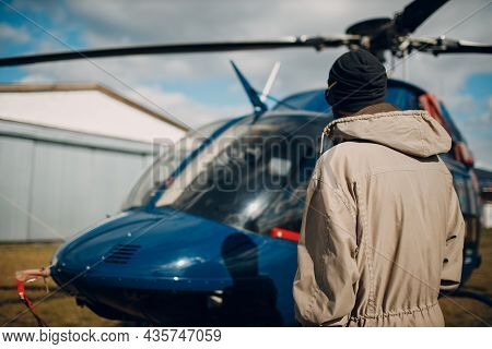 Portrait Of Helicopter Pilot Standing Near Vehicle In Field Airport.