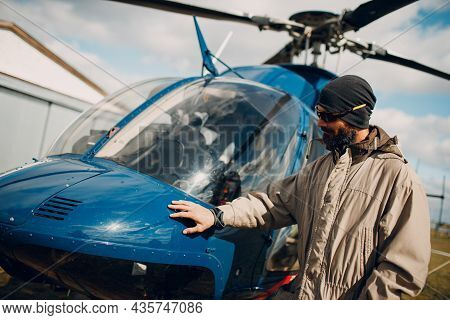 Portrait Of Helicopter Pilot Standing Near Vehicle In Field Airport.