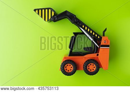 Orange Toy Loader On Green Background, Mini Loader, Toy Industrial Car, Plastic Front Wheel Loader.