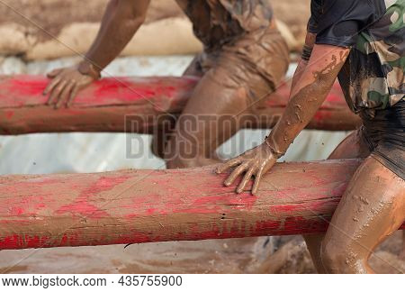 Mud Race Runners. Participants On The Tree Trunk, Catches Balance Above The Pit Full Of Water