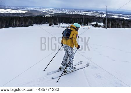 Young Woman In Yellow Jacket And Ski Helmet Skiing On A Mountain Slope, Winter Sports, Alpine Skiing