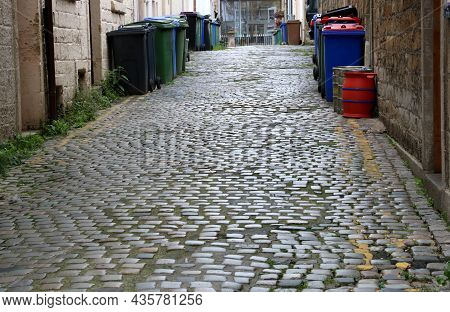 City Back Alleyway With Cobbles Beer Barrels And Bins