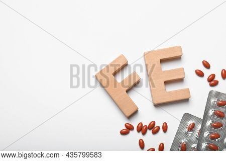 Wooden Letters Fe And Pills On White Background, Top View. Anemia Concept