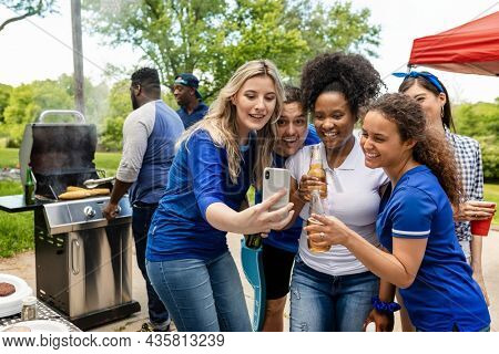 Friends watching the game on a phone at a tailgate party