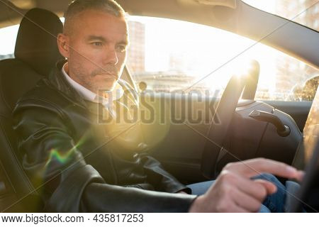 Mature man touching tablet diaplay while sitting in car and choosing destination point