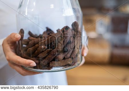A Woman Holds Croutons In A Glass Jar. Eco Shop Without Plastic Waste.