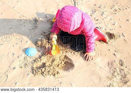 Child Girl Playing By The Sea In Autumn. A Girl In A Red Jacket In A Beautiful Autumn On The Seashor