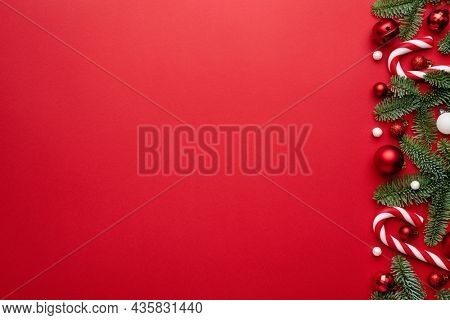 Red background with holiday border, Christmas balls, and a candy cane for Christmas design. Blank with a copy space for text