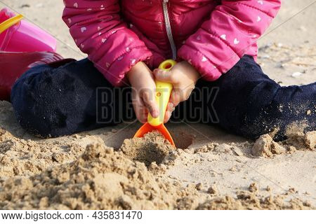 Child Girl Playing By The Sea In Autumn. A Girl In A Red Jacket In A Beautiful Autumn On The Seashor