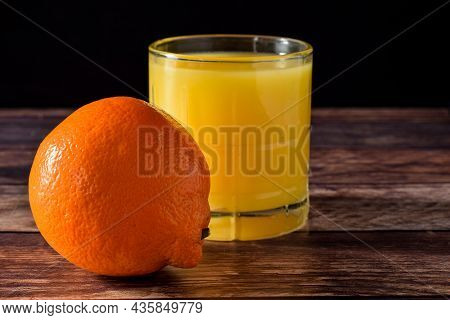 An Orange With A Orange Juice Against A Black Background