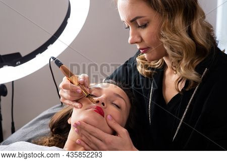 Young woman making lips tatouage in a dressing makeup room. Lips tatouage process .Woman making lips blushing. Make-up artist in beauty studio doing makeup for beautiful girl. Making mua.