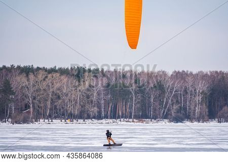 Kite Surfer Ride On Snowboard. Snowkiting In The Snow On Frozen Lake.
