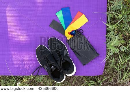 View From Above Of Fitness And Sport Equipment. Sneakers, Elastic Rubber Band On Exercise Mat Backgr
