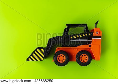 Orange Toy Loader On Green Background, Mini Loader, Toy Industrial Car, Plastic Front Wheel Loader.