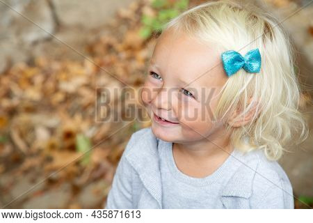 Smiling Blond Blue-eye Girls Portrait. Autumn Walk In Art. Blu Hairpin Bow. Happiness Concept. Child