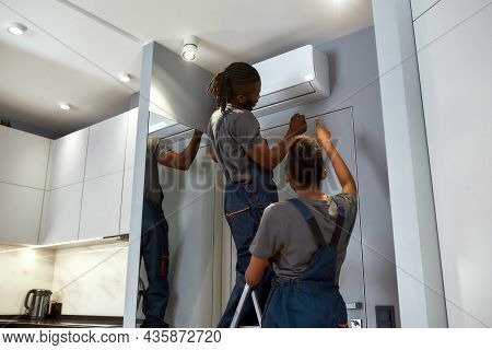 Back View Service Company Workers Installing Air Conditioner. Woman Senior Technician Advising Her M