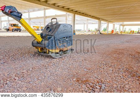 Used Plate Compactor, Vibratory Hammer, Jumping Jack Machine, Power Tool Placed In Shadow At Constru